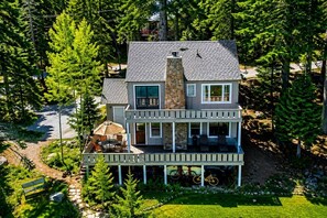 A two-story house with a stone chimney, a balcony, and a patio with outdoor furniture.