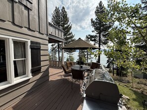 Eine Terrasse mit Grill, Gartenmöbeln und Blick auf den See.