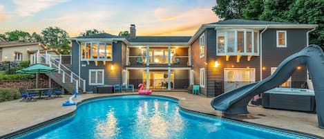 A residential property with a swimming pool, a slide, and a covered patio area.