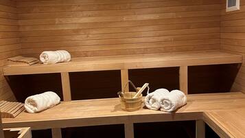 Una sala de sauna con bancos de madera y suelo de madera, y un techo con iluminación empotrada.