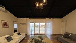 A spacious living room with two sofas, a coffee table, and a large window with a view. - 3 bedrooms in the farm with stay in Desert Hut

 (Ras Al-Khaimah)