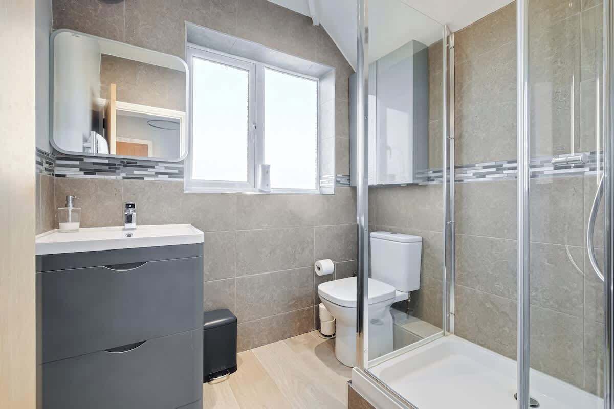 Un baño moderno con cabina de ducha de vidrio, inodoro y tocador con cajones.