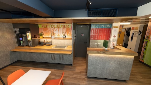 A reception area with a counter, seating, and a coffee machine. - Accueil Hotel Besançon (Besancon)