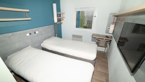 A compact room with two beds, a small desk, a window, and a TV. - Accueil Hotel Besançon (Besancon)
