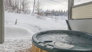Ein Whirlpool auf einer Holzterrasse mit verschneiter Landschaft im Hintergrund.