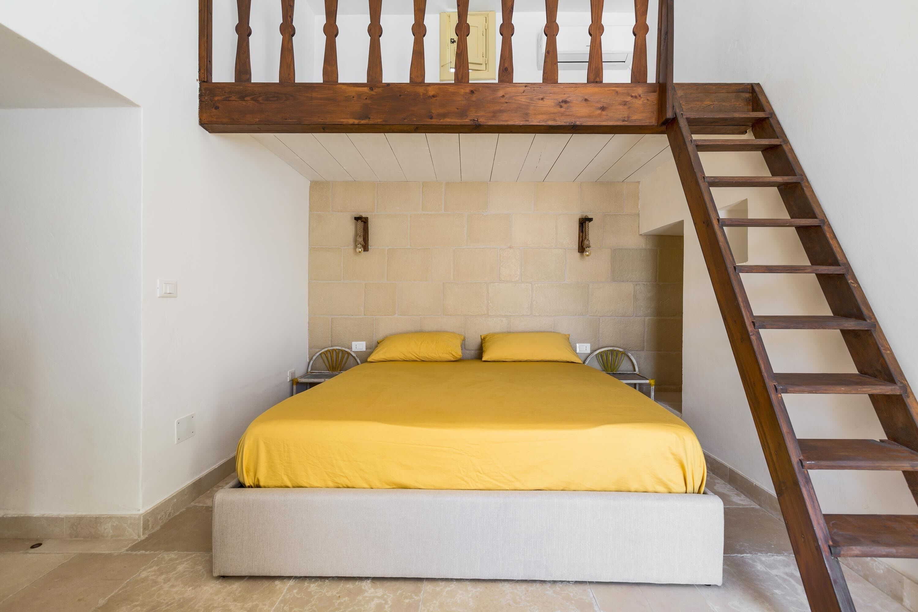 A bedroom with a bed, a wooden ladder, and a tiled wall.
