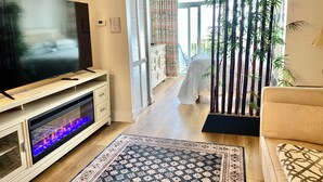 A living room with a flat-screen TV, a fireplace, a sofa, and a decorative plant arrangement. - Oceanfront Condo, Balcony, Pools, Beach Access, Walk to Restaurants & Boardwalk  (Myrtle Beach)