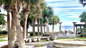 A landscaped area with palm trees, planters, and a fountain. - Oceanfront Condo, Balcony, Pools, Beach Access, Walk to Restaurants & Boardwalk  (Myrtle Beach)