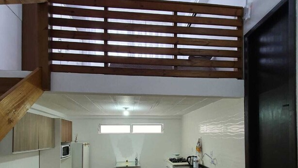 Apartament compacte amb petita cuina, zona de menjador i saló amb sofà i llit.