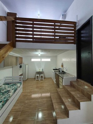 Un apartamento funcional con kitchenette, comedor y un pequeño espacio de estar con sofá y cama.