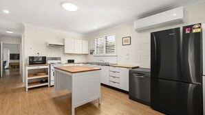A modern kitchen with white cabinetry, a black refrigerator, and a wooden countertop.