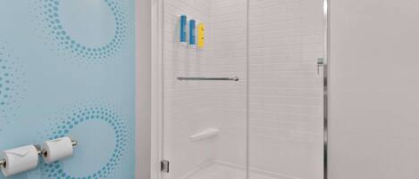 Un baño moderno con cabina de ducha de vidrio, paredes de azulejos blancos y una pared azul con un diseño circular.