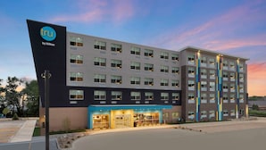 A modern hotel building with a prominent 'tru by Hilton' sign, multiple floors, and a well-lit entrance.