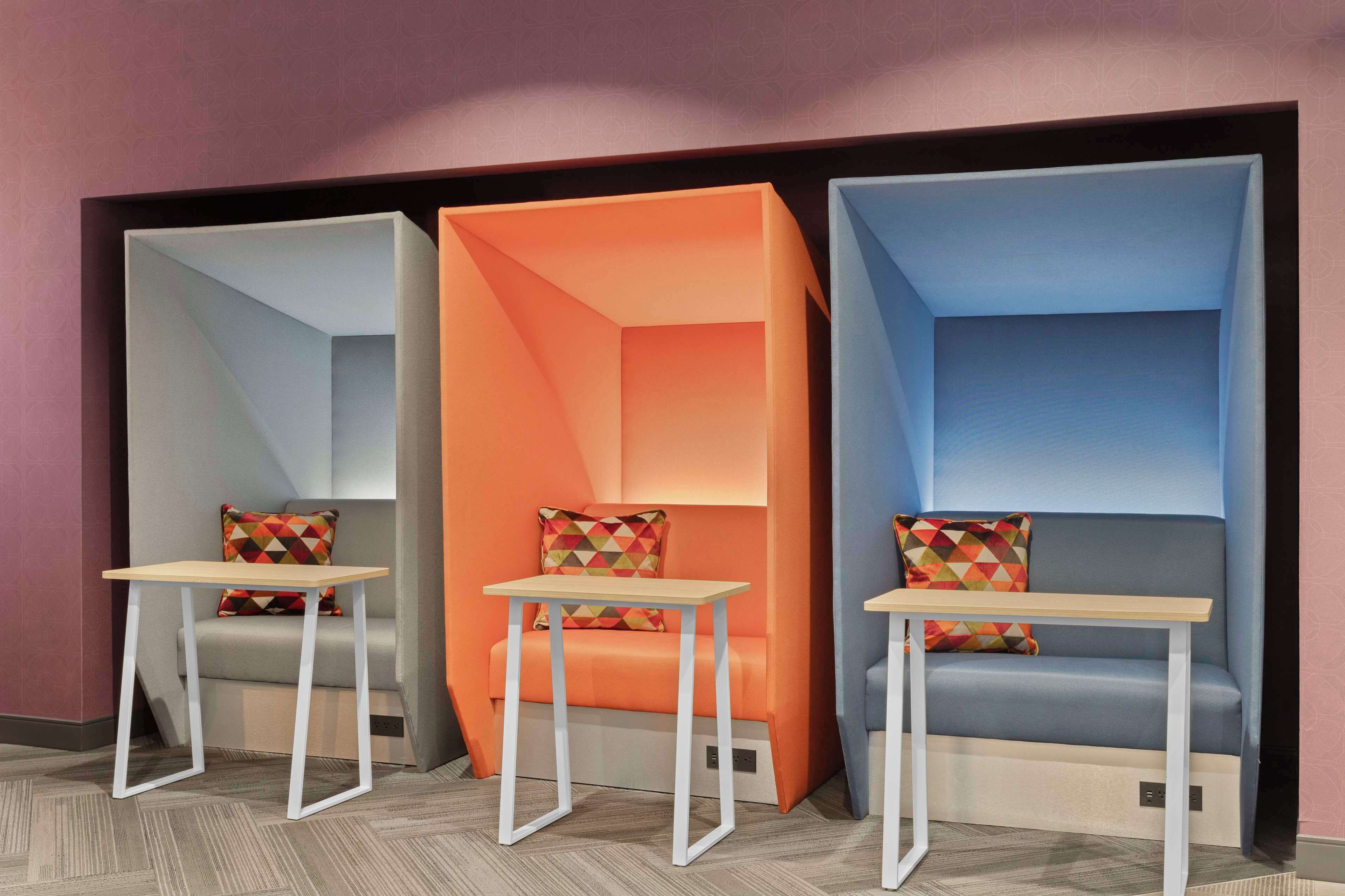 Una habitació moderna amb tres zones d'seients, cadascuna amb una paleta de colors diferent i una taula petita.