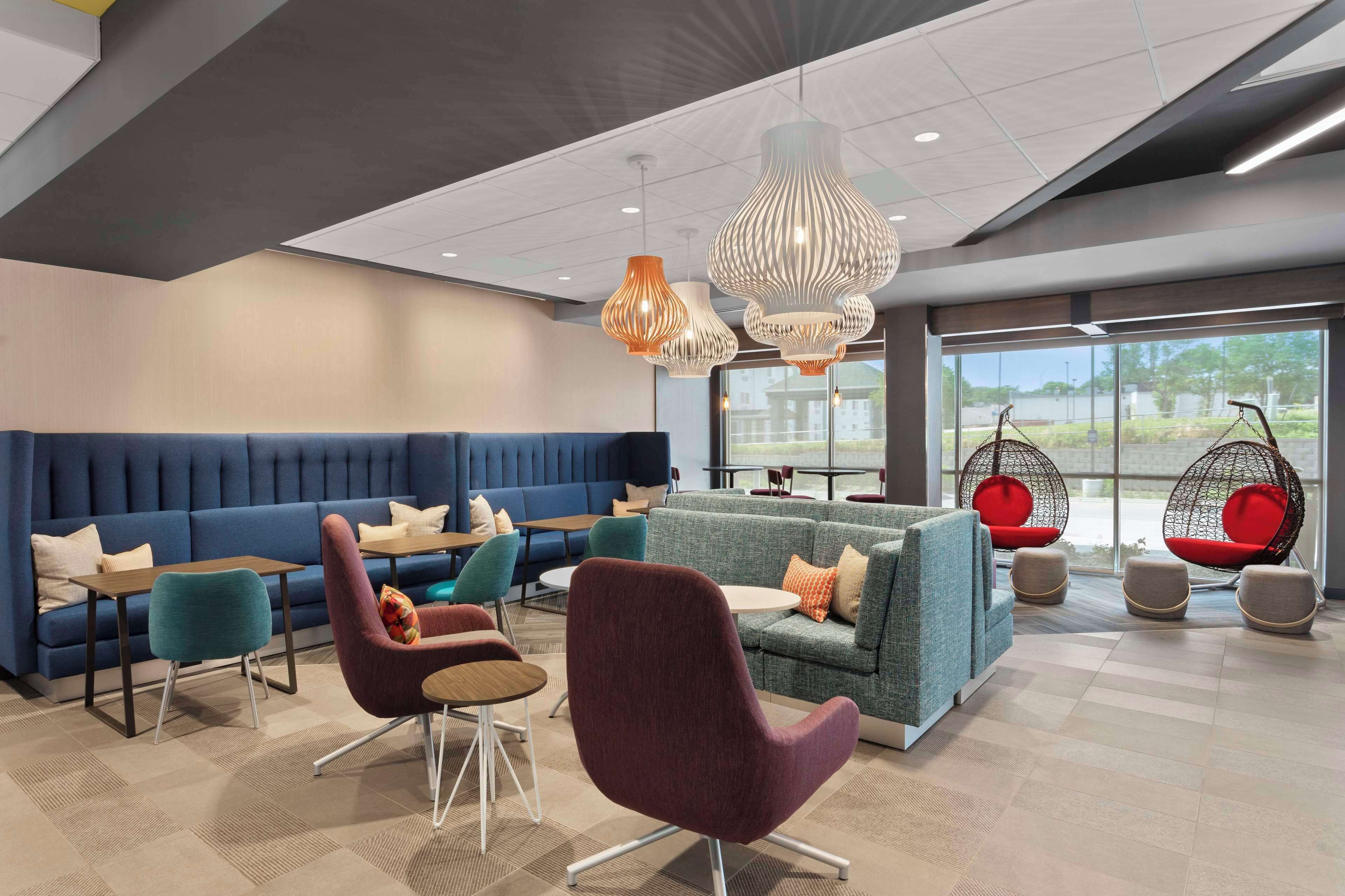 A modern lounge area with seating arrangements, including sofas and chairs, and hanging chairs.