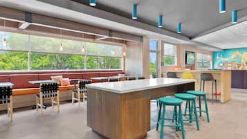 A modern indoor space with a central island, seating area, and large windows.