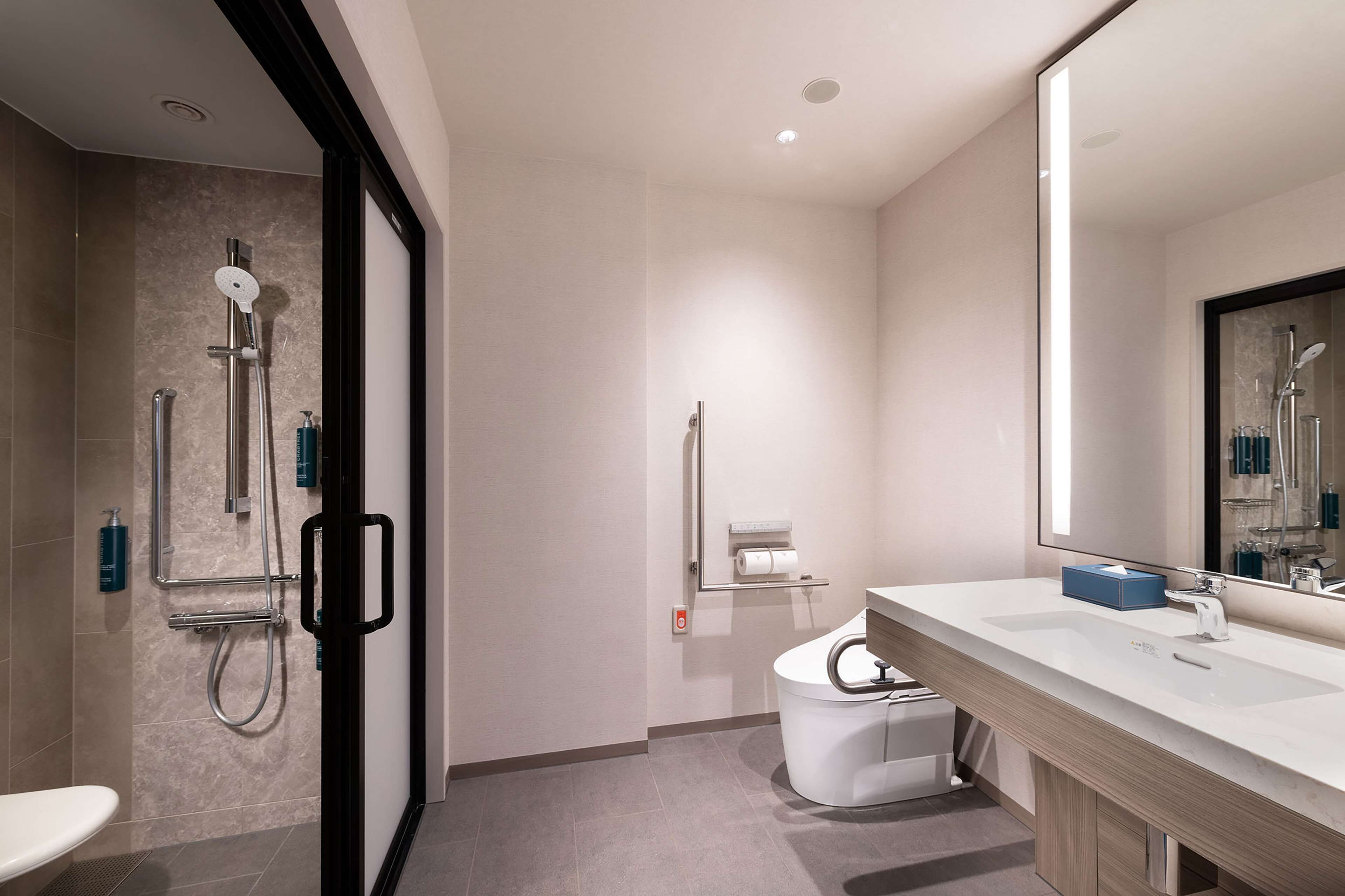 A modern bathroom with a shower, toilet, and sink.