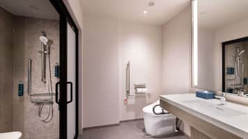 A modern bathroom with a shower, toilet, and sink.