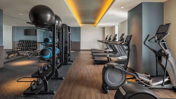 Un gimnasio con cintas de correr, elípticas y pesas sueltas.