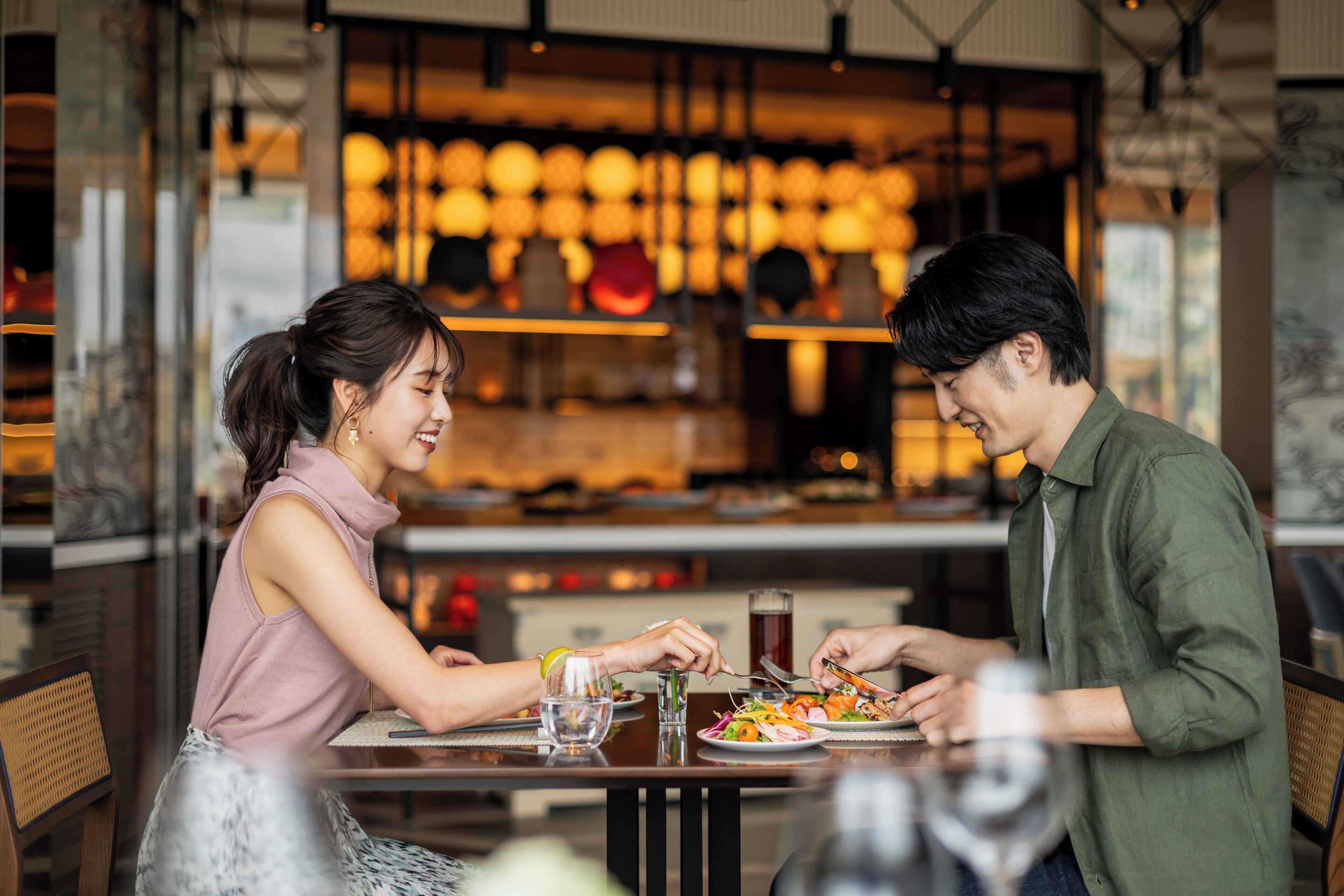 A couple dining at a restaurant with a modern interior and warm lighting.