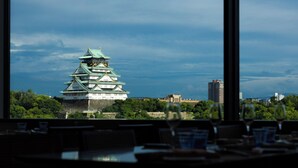 A view of Osaka Castle from inside a building, with a dining area in the foreground. - DoubleTree by Hilton Osaka Castle (Osaka)
