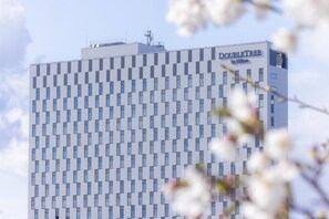 Un moderno edificio de hotel con una fachada geométrica distintiva y el nombre "DOUBLETREE by Hilton" a la vista.