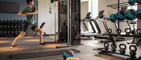 Un gimnasio con equipo de ejercicio, cintas de correr y pesas.