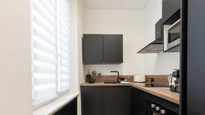 Une cuisine moderne avec des meubles de couleur sombre, un plan de travail en bois, un four encastré et un four à micro-ondes.