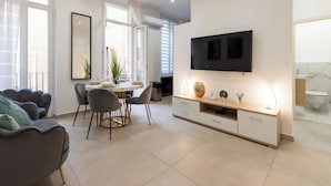 Un salon moderne avec un coin repas, un téléviseur fixé au mur et une vue sur le balcon.