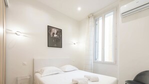 Une chambre d’hôtel avec un lit, une chaise, une fenêtre et un climatiseur.