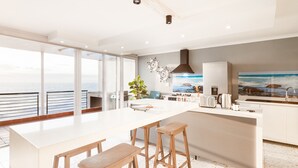 Une cuisine moderne dotée d’un grand îlot central, de tabourets de bar et offrant une vue sur la mer.