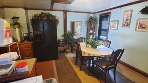 A kitchen with a refrigerator, a dining table with chairs, and a coffee maker. - Big Beautiful House Close to Downtown Indianapolis with outdoor firepit  (Indianapolis)