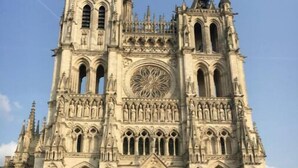Une grande cathédrale dotée de deux portes rouges et ornée de sculptures complexes en pierre.