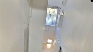 Eine Treppe mit weißen Geländern und einem Holzboden, die zu einem Raum mit Fenster und Tür führt.
