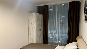 Une chambre d’hôtel avec un lit, une armoire et une fenêtre avec des rideaux.