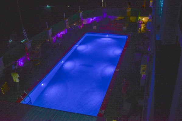 Piscina rectangular con un tono azul, rodeada por un muro bajo y varias estructuras.