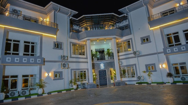 A multi-story hotel with a central entrance, balconies, and outdoor lighting.