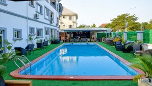 A swimming pool with a red border, surrounded by artificial grass and outdoor furniture.