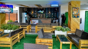 A modern bar area with wooden furniture, green artificial grass, and a bar counter.