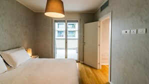 A bedroom with a bed, a hanging light fixture, a nightstand, and a sliding door leading to a balcony.
