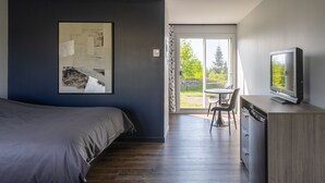 A modern bedroom with a bed, a television, and a dining area with a table and chairs.