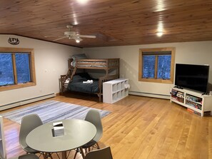 Una habitació acollidora amb un llit superposat, una televisió, una prestatgeria i una zona de menjador.