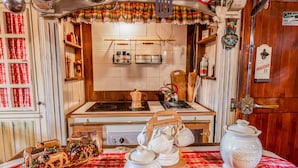 A kitchen with a red and white checkered tablecloth, a stove, and various kitchen utensils. - 1 Bedroom Cabin in Isola (Isola)