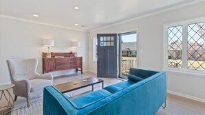 A living room with a blue sofa, a wooden dresser, and a lamp. - Tulsa Vintage Chic Cottage |King Bed •Expo•TU•Dtwn (Tulsa)
