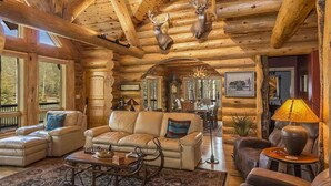 L’intérieur d’une cabane en rondins, avec un canapé en cuir, une table basse et un lustre.