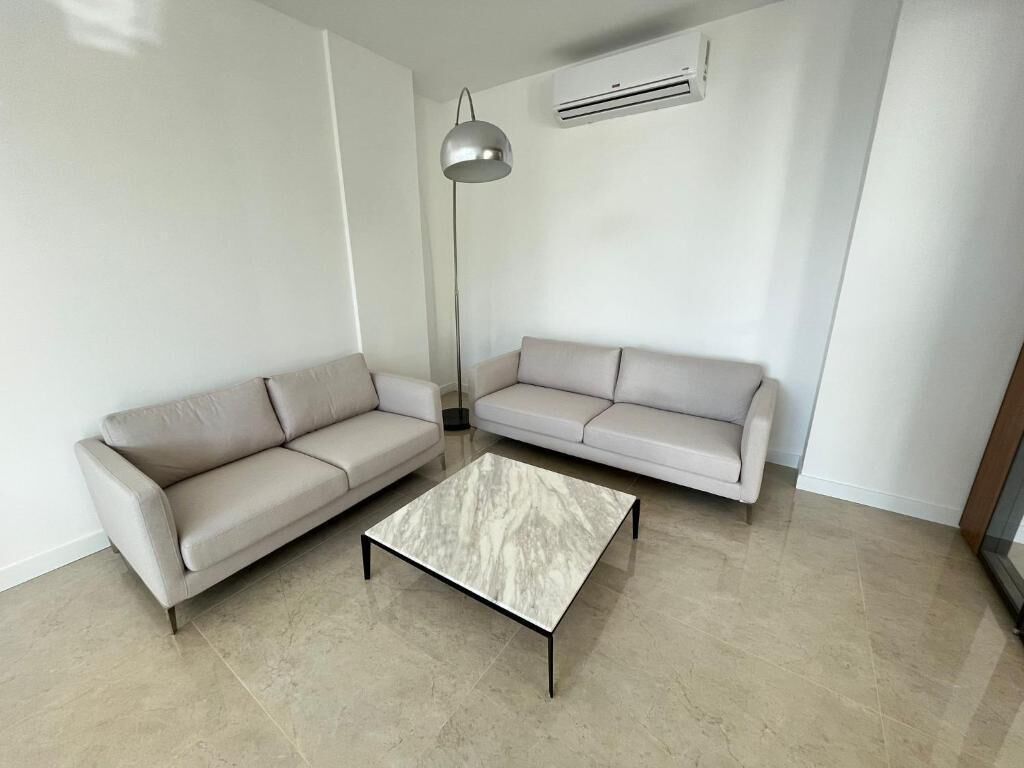 Una sala de estar moderna con dos sofás y una mesa de centro de mármol.