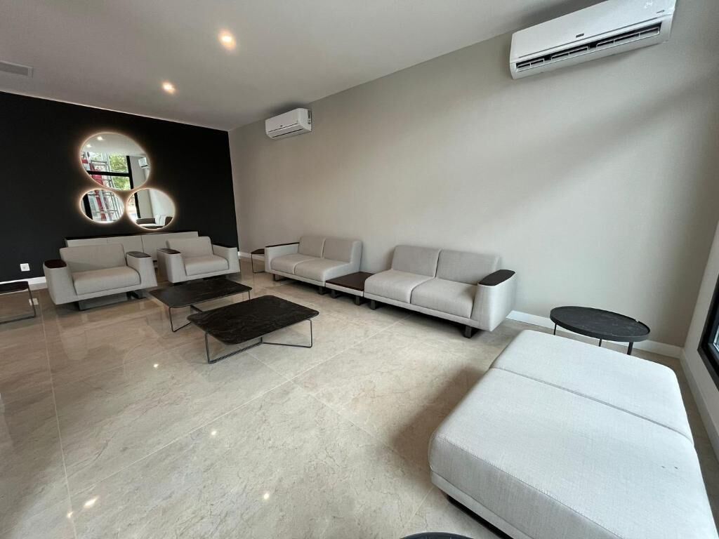 A modern living room with a sectional sofa, a coffee table, and a round mirror on the wall.