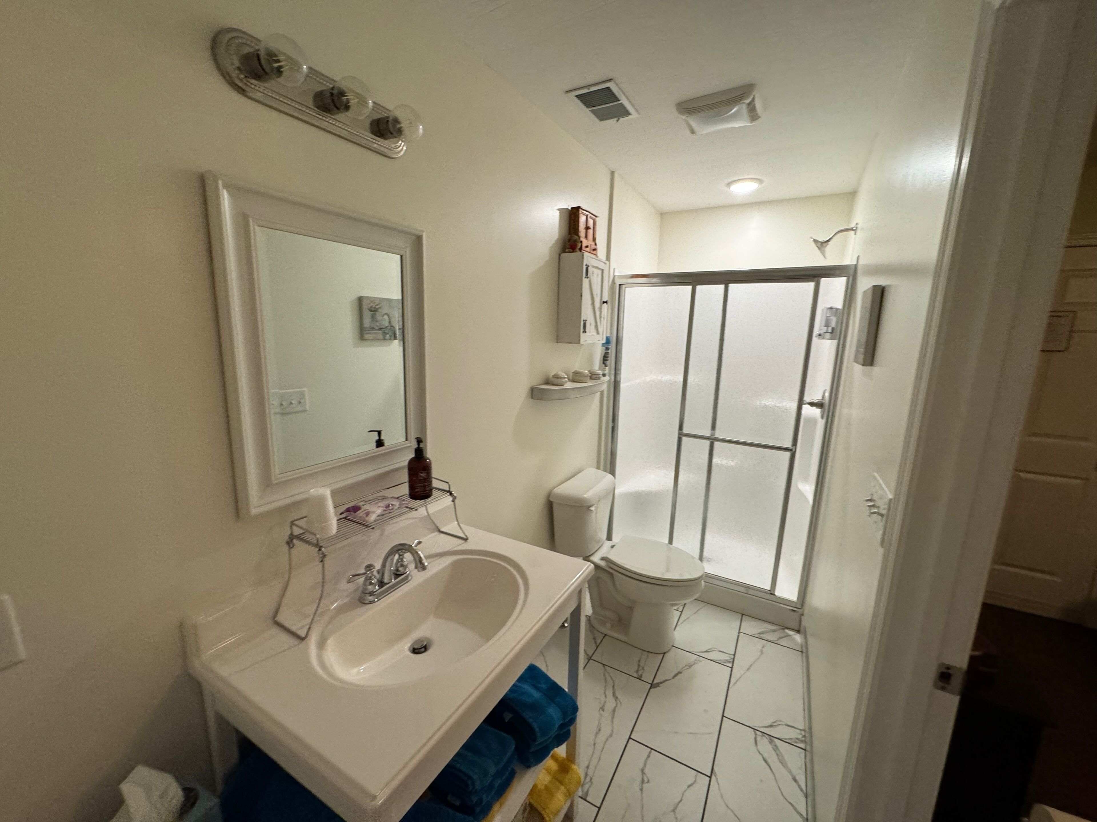 A bathroom with a sink, mirror, shower, and toilet.