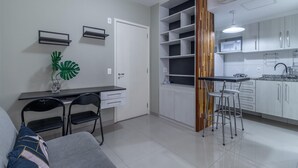 A compact kitchen with white cabinets, a built-in stove, and a dining area with a small table and chairs. - Av0909 in S o Paulo (São Paulo)