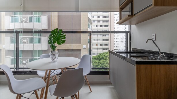 A modern kitchen with a round table and chairs, a large window with a view of buildings, and a plant on the table. - Wbe710 in S o Paulo (São Paulo)